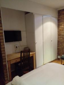 Dormitorio con cama, escritorio y TV en Tshidiso Guesthouse, en Centurion