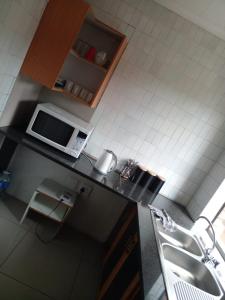 a kitchen with a counter with a microwave and a chair at Tshidiso Guesthouse in Centurion