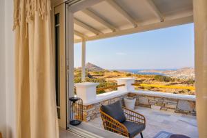 a balcony with a chair and a view of the ocean at Anemos house Ios in Ios Chora