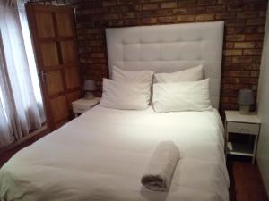 Un dormitorio con una gran cama blanca con una toalla. en Tshidiso Guesthouse, en Centurion