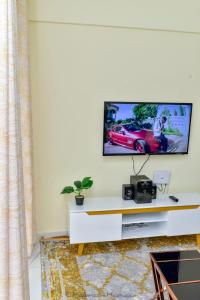 ein Wohnzimmer mit einem TV an einer weißen Wand in der Unterkunft Sandalwood Garden in Nairobi