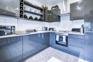 a large kitchen with stainless steel cabinets and appliances at Modern 2-Bedroom - 2 Bathroom Apartment in Waltham Abbey-Gated Car Park-Fast Internet in Waltham Abbey