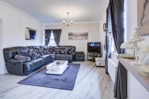 a living room with a leather couch and a tv at Modern 2-Bedroom - 2 Bathroom Apartment in Waltham Abbey-Gated Car Park-Fast Internet in Waltham Abbey