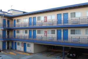 ein Apartmenthaus mit blauen Türen und einem Parkplatz in der Unterkunft Surf Motel in San Francisco