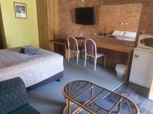 Habitación de hotel con cama, escritorio y lavabo. en Alyn Motel, en Gunnedah