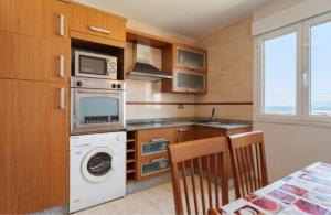 Una cocina con estufa, lavadora y secadora. en CASA MARIÑO, en Portosín