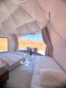 RUM ATANA lUXURY CAMP في وادي رم: غرفة نوم بسريرين في خيمة كبيرة