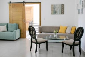 uma sala de estar com um sofá, 2 cadeiras e uma mesa de vidro em Sunset Apartment D em San Felipe de Puerto Plata