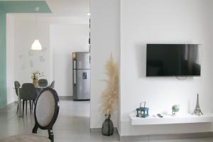 uma sala de estar com uma mesa e uma televisão na parede em Sunset Apartment D em San Felipe de Puerto Plata