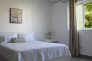 um quarto branco com uma cama e uma janela em Sunset Apartment D em San Felipe de Puerto Plata