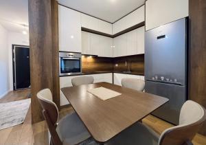 a kitchen with a wooden table and white cabinets at Apartment with balcony in Gjakove