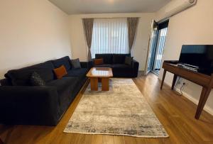 a living room with a black couch and a piano at Apartment with balcony in Gjakove