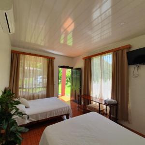 a bedroom with two beds and a table and windows at Lumbres Arenal in Fortuna