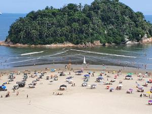 un groupe de personnes sur une plage avec une île dans l'établissement Aqui é pé na areia, à Santos