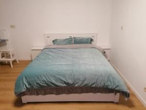 Schlafzimmer mit einem Bett mit blauer Decke in der Unterkunft La Maison Heureuse in Châtelet