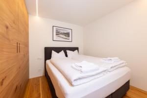 a bedroom with a white bed with white towels on it at New! Cozy, central apartment with a stunning view in St. Moritz