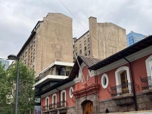 an old building with two tall buildings in the background at Stylish apartment dowtown 78m2 in Santiago