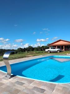 a blue swimming pool with a car in the background at Pousada Colina das Maritacas in São Thomé das Letras