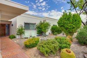 a garden in front of a white building with plants at Tucson Townhome with Shared Pool in 55 and Community! in Tucson