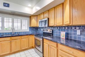 a kitchen with wooden cabinets and blue tiles on the wall at Tucson Townhome with Shared Pool in 55 and Community! in Tucson