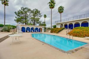 a swimming pool with a table and palm trees at Tucson Townhome with Shared Pool in 55 and Community! in Tucson