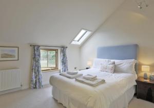 a bedroom with a bed with a blue headboard and a window at Harrow Cottage in Yoxford