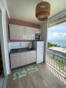 cocina con armarios blancos y balcón con vistas al océano en Kay Louisette, en Le Diamant