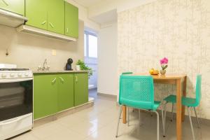 una cocina con armarios verdes, mesa y sillas en Fliphaus Juncal 2800 - 2 Bd In Alto Palermo en Buenos Aires