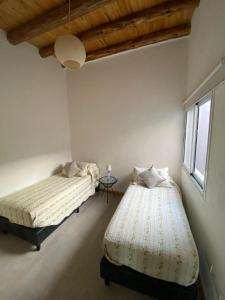 1 dormitorio con 2 camas, mesa y ventana en Los Andes de Uco en La Consulta