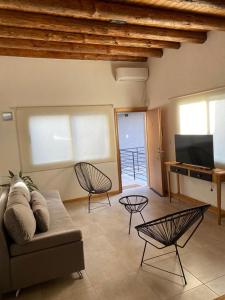 uma sala de estar com um sofá e duas cadeiras e uma televisão em Los Andes de Uco em La Consulta