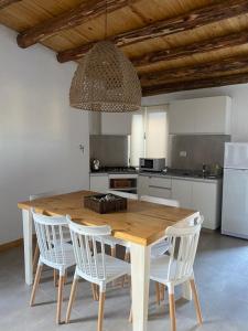 a kitchen with a wooden table and white chairs at Los Andes de Uco in La Consulta