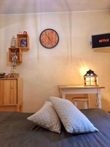 a pillow sitting on a bed with a clock on the wall at [*Corazón*] il Loft del cuore in Filettino
