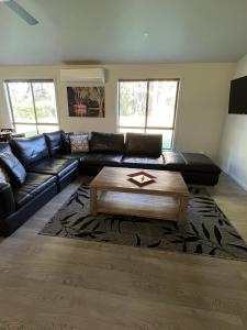 a living room with a black leather couch and a coffee table at Greenways Holiday Units in Tocumwal
