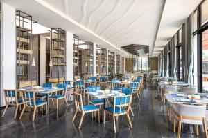 un restaurante con mesas azules, sillas y libros en Four Points by Sheraton Wuchuan, Loong Bay, en Wuchuan