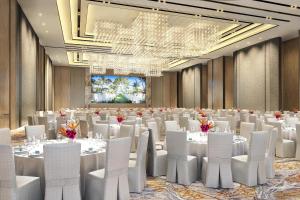 吴川吴川鼎龙湾福朋喜来登酒店的舞厅,配有白色的桌子和白色的椅子,还有舞台 更多37张照片