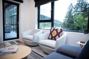a living room with two white chairs and a large window at Le Refuge - Revelstoke Condo with Hot Tub in Revelstoke