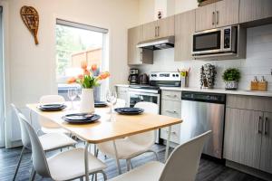 a kitchen with a wooden table and white chairs at Reved Up & Out - Remarkable Two Bedroom Condo in Revelstoke