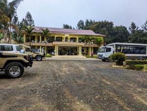 una grande casa con un autobus parcheggiato di fronte di Mvuli Hotels Arusha ad Arusha