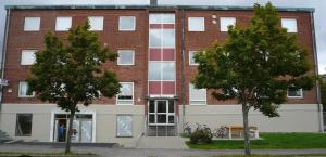 a large brick building with trees in front of it at Noah Longstay Borås in Borås