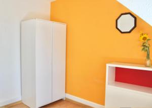 a white cabinet in a room with an orange wall at Swiss Tranquility Suites in Aarau
