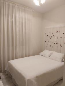 a white bedroom with a bed and a window at Casa Serena in Villanueva del Ariscal