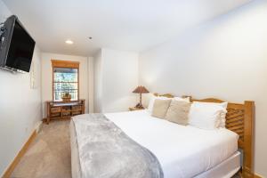a bedroom with a white bed and a flat screen tv at Bear Creek Lodge 110A in Telluride