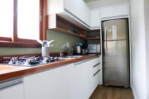 a kitchen with a stainless steel refrigerator and white cabinets at Lar do Vinil - Conforto e ótima localização in Nova Petrópolis