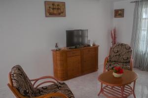 - un salon avec une télévision, 2 chaises et une table dans l'établissement Vila Paradise Sea & Swimming Pool View, à Beirona