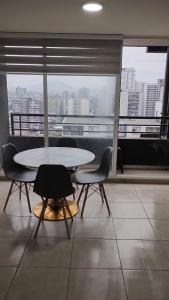a table and chairs in a room with a large window at Edificio Núcleo espectacular departamento in Santiago