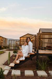 una sposa e uno sposo seduti su una panchina al tramonto di Indomito Resort & Hotel Boutique a Valle de Guadalupe