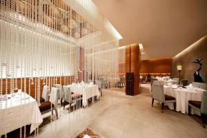 uma sala de jantar com mesas e cadeiras brancas e uma parede de vidro em Sheraton Xi'an Hotel em Xi'an