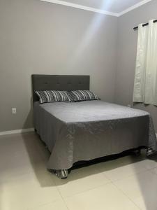 1 cama en una habitación de color blanco con faldas pectespectralessenalsenal en Apartamento Fátima PARA FAMÍLIA, en Balneário Camboriú