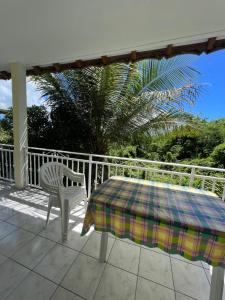 une table et une chaise assises sur une terrasse couverte dans l'établissement Maison type F4 vue sur mer, au Gosier