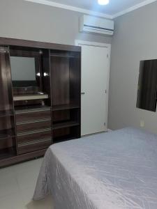 1 dormitorio con 1 cama y vestidor con TV en Apartamento Fátima PARA FAMÍLIA, en Balneário Camboriú